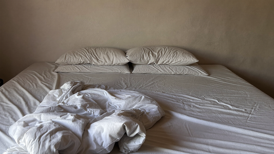 Onopgemaakt bed met een opzij geschoven dekbed in het zachte licht van de vroege ochtend