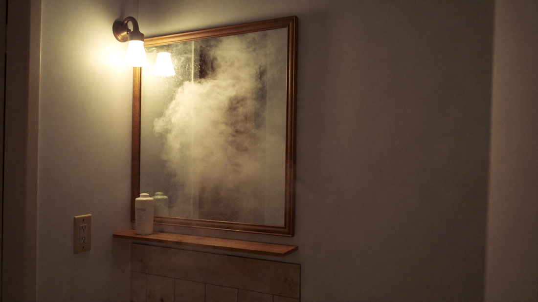 Fogged-up bathroom mirror in warm lamplight